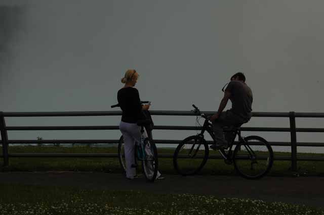 a biking couple is sihouetted by the mist of Horseshoe Falls